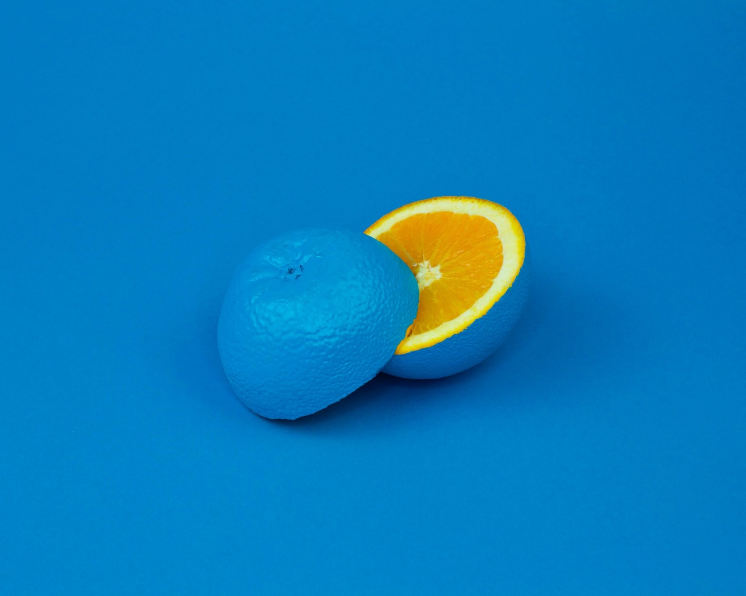 Creative concept of a blue-painted orange cut open to reveal a bright orange interior.