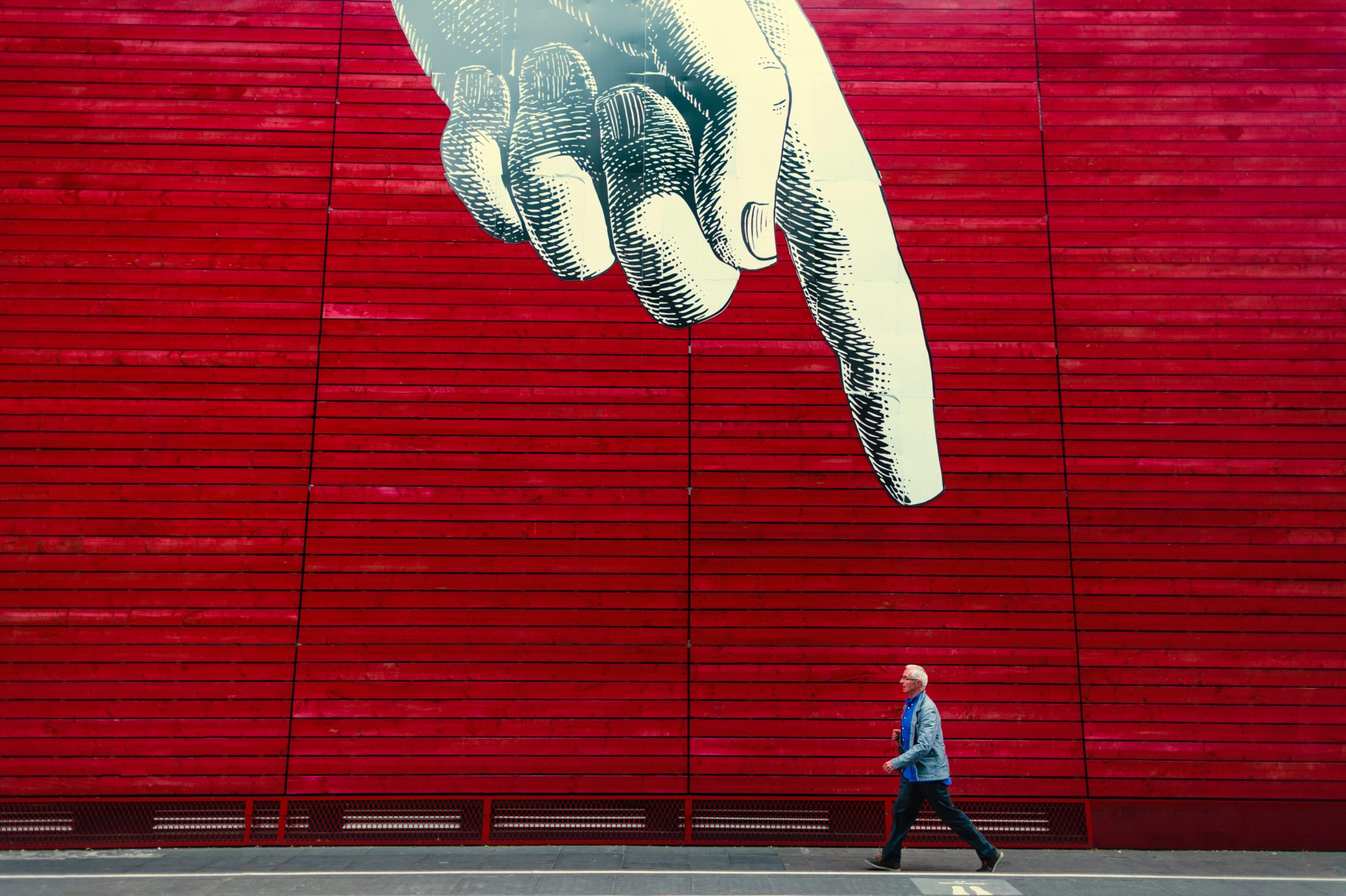 Animated giant hand pointing at a man walking to represent that custom websites are better than templated websites.
