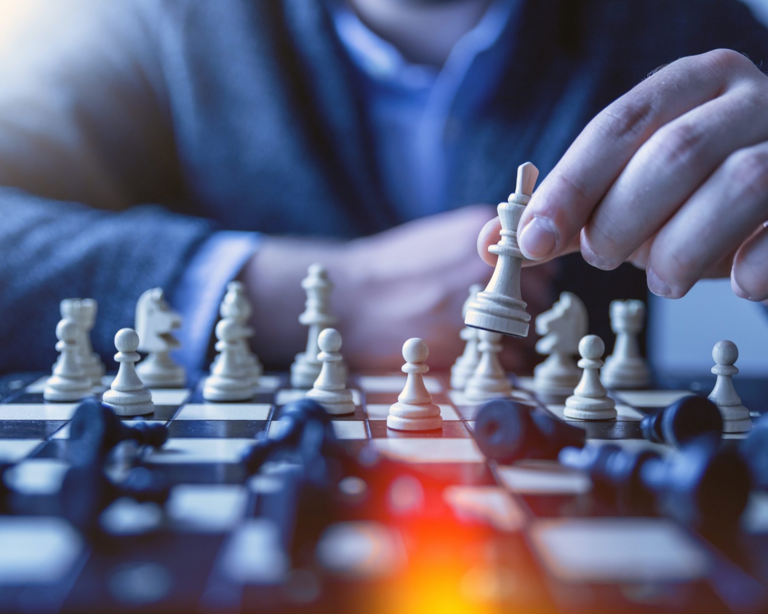 Person moving a chess piece on a chessboard, symbolizing marketing strategy and decision-making.