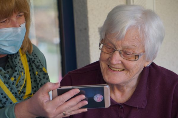 Caregiver showing something on her smart phone to a senior.